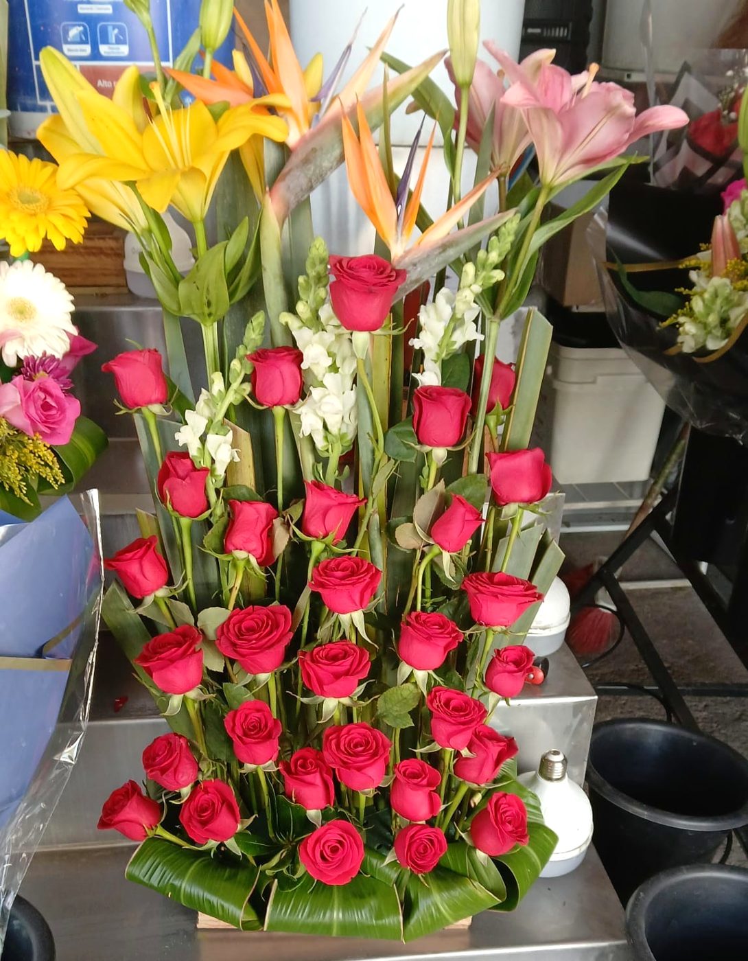 Rosas rojas y lirios en florero